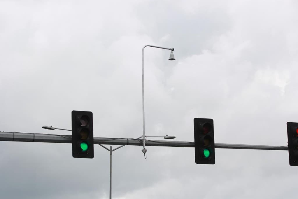 Overhead traffic signal heads against a cloudy sky