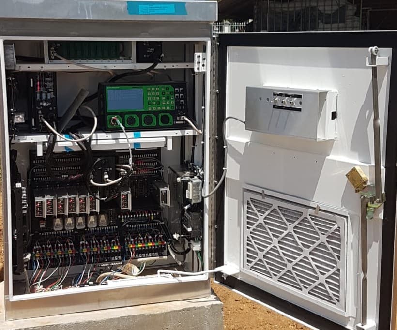 Open traffic signal controller cabinet with wiring, modules, relays, and a green front-panel controller