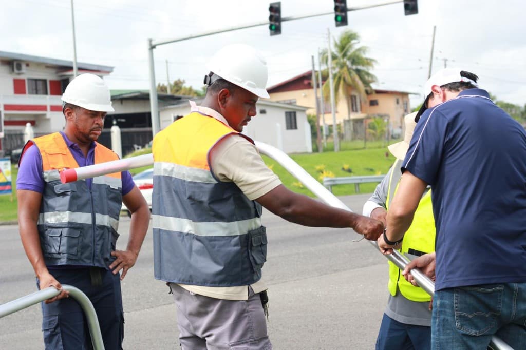 Crew lifting and aligning a curved mast arm for signal installation near an intersection